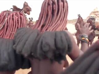 Afrikietiškas himba moterys šokis ir sūpynės jų saggy papai aplink
